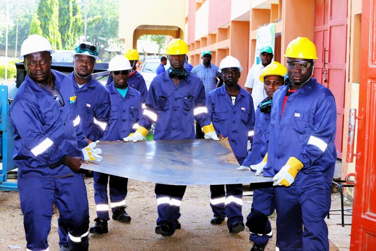 Photo of the trainess machine fabricators moving galvanized metal sheets at the IAR workshop in Zaria.